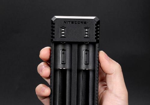 Chargeur nitecore dans une main sur fond noir