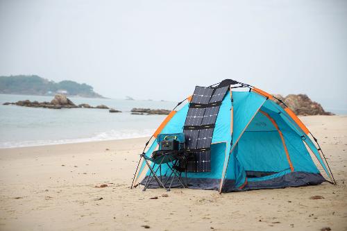Tente, panneau solaire et Power station NPS exposés sur une plage